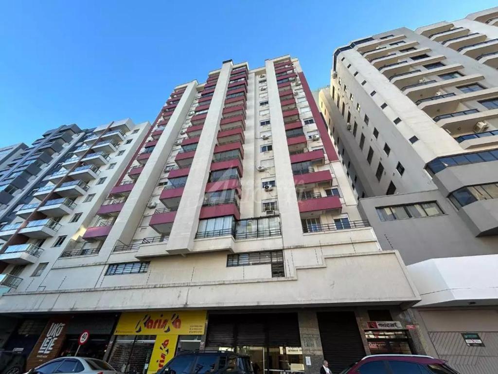 a tall building with cars parked in front of it at Apartamento central 1 quarto in Passo Fundo