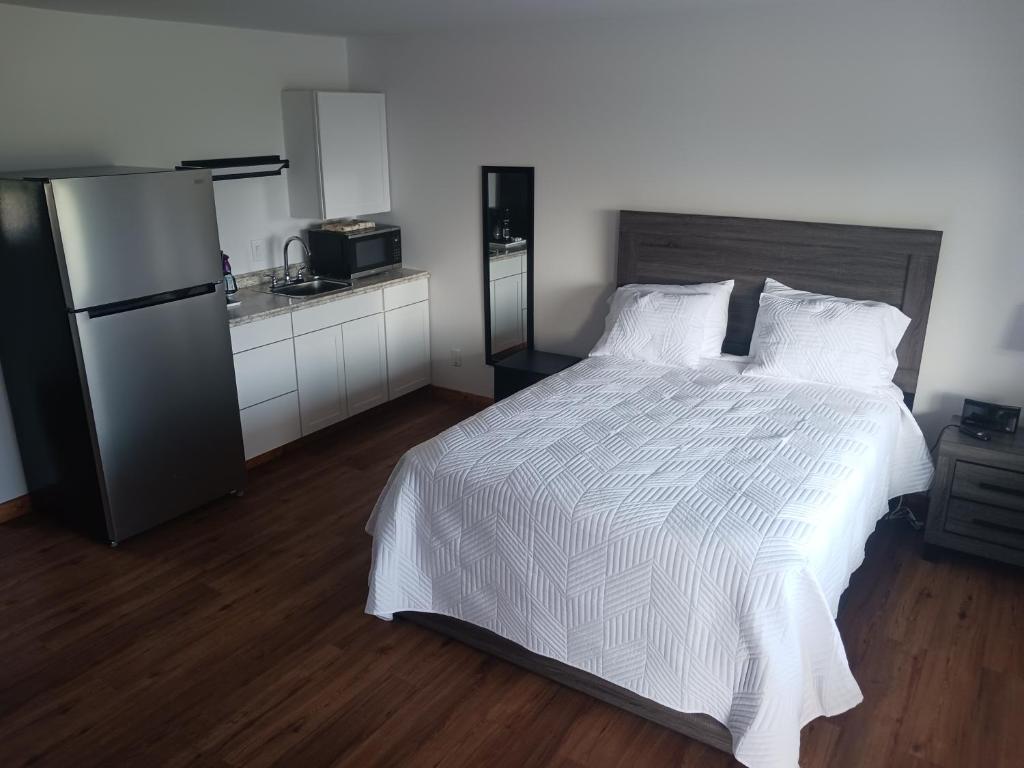 a bedroom with a white bed and a refrigerator at Chapel Hill Motel in Moran