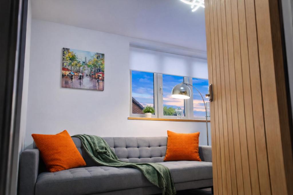 a living room with a gray couch with orange pillows at City Centre Apt with FREE PARKING in Doncaster