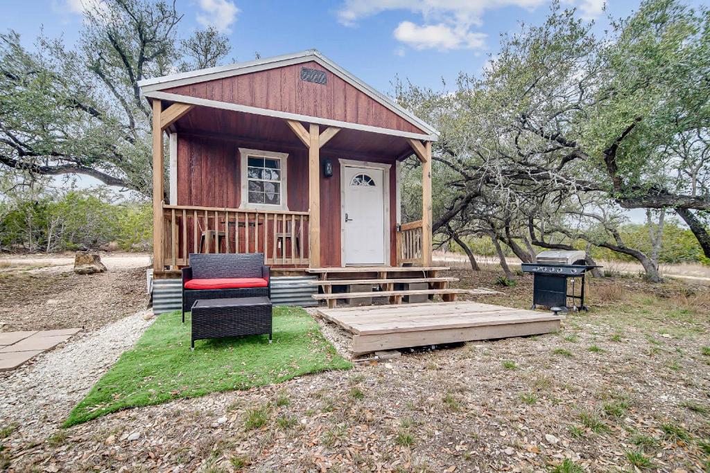 a tiny house with a porch and a chair in a field at Hill Country Cabin 4 in Canyon Lake