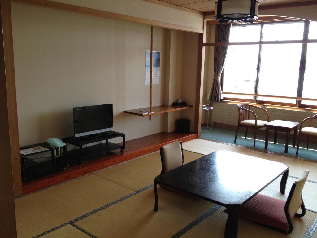 uma sala de estar com uma mesa e uma televisão em Iyashinoyado Rodem em Morioka