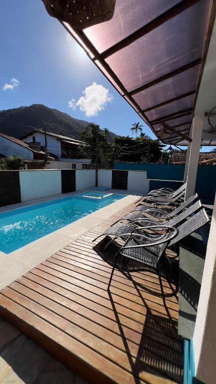 a deck with chairs next to a swimming pool at Pousada Tribo Ubatuba in Ubatuba
