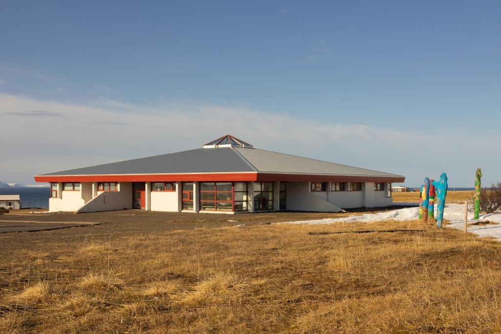 a large white building with a grass field at FarNorth Hostel in Bakkafjörður