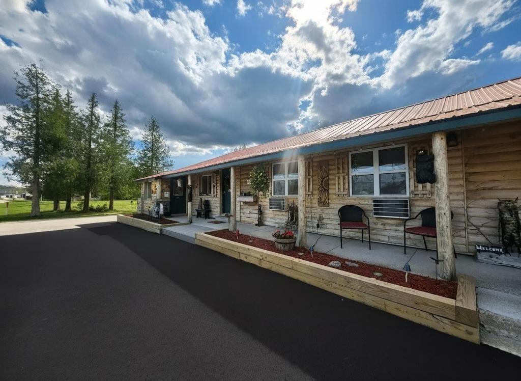 a log cabin with a porch and a driveway at Moosewood Inn in Saint Ignace