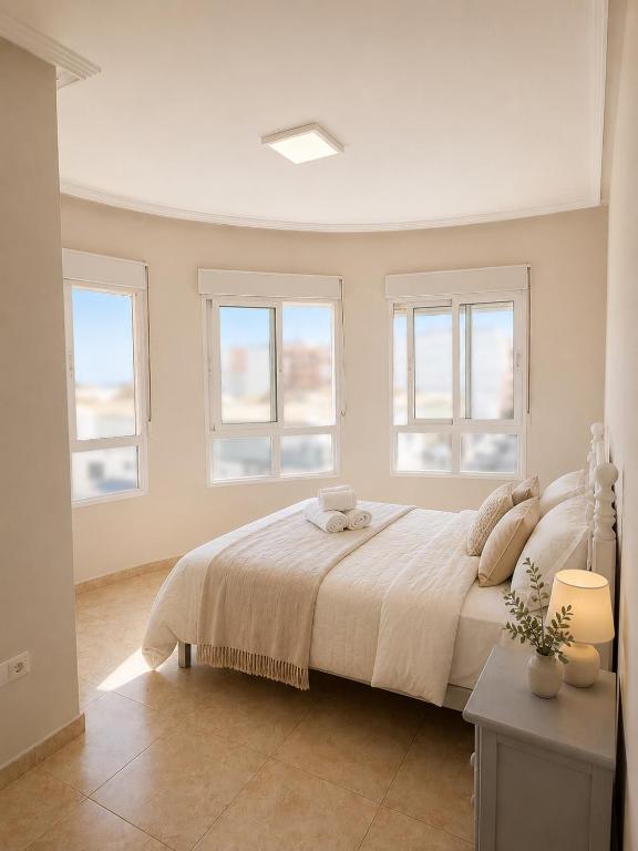 a white bedroom with a large bed with windows at Raffaelas vacation apartment in Torrevieja
