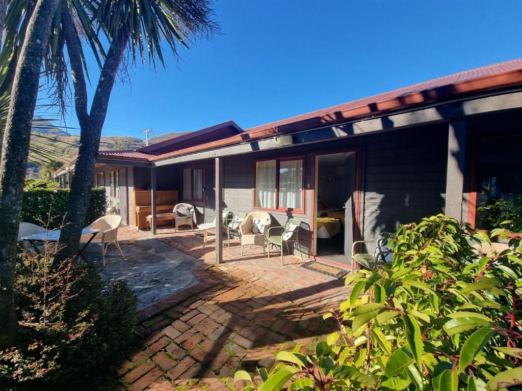a house with a patio with chairs and a palm tree at #6 Glenorchy Alpine Suite in Glenorchy