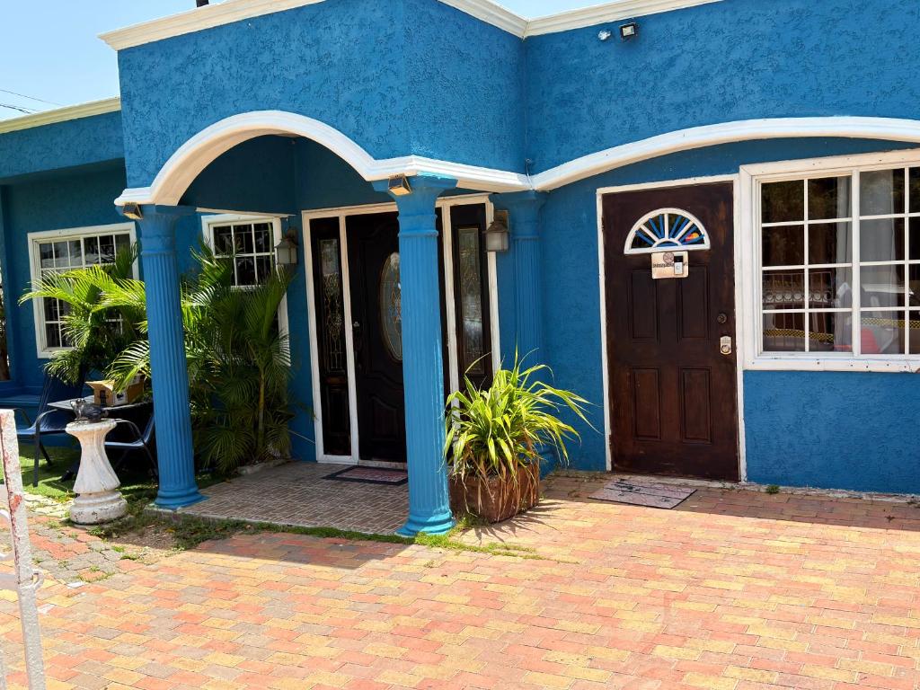 a blue house with a wooden door in front at Swimaz Gateway in Harbour View