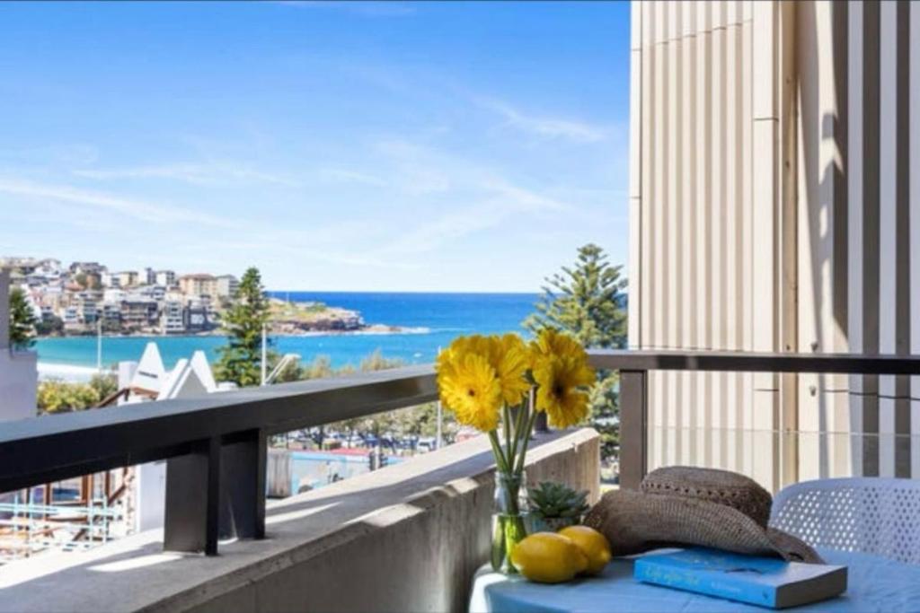 a vase with yellow flowers on a table on a balcony at Modern Beach Ocean View 1 BDR Parking Balcony AC in Sydney