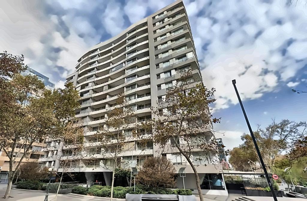 a tall apartment building with a tree in front of it at Apart Lyon Suite in Santiago
