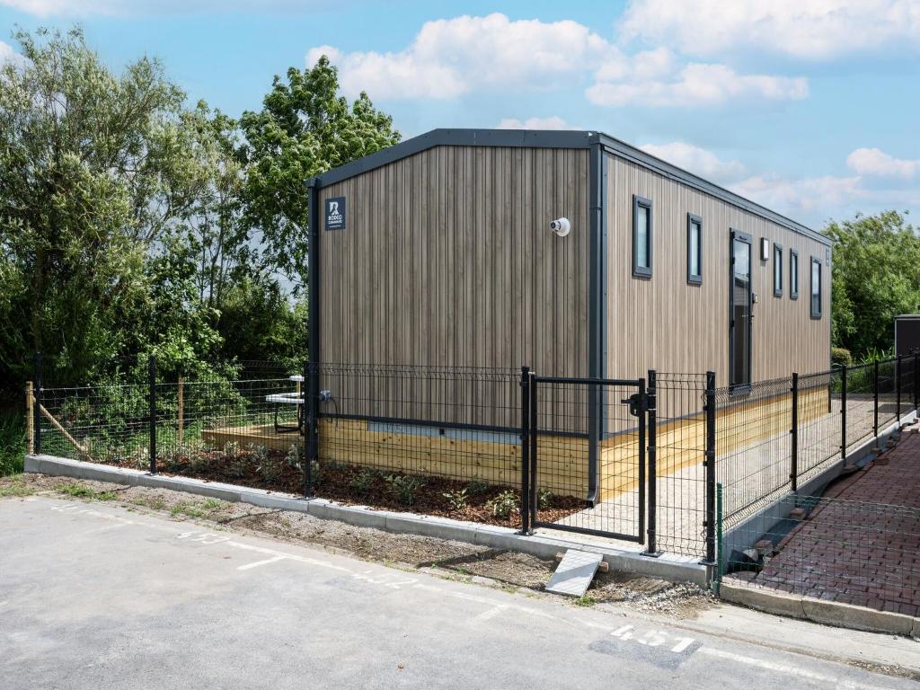 a small building with a fence next to a street at New Vennepark caravan 463 6p in De Haan