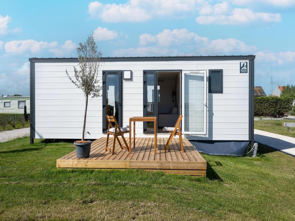 a tiny house with two chairs and a table at Caravan Bredene by the sea in Bredene