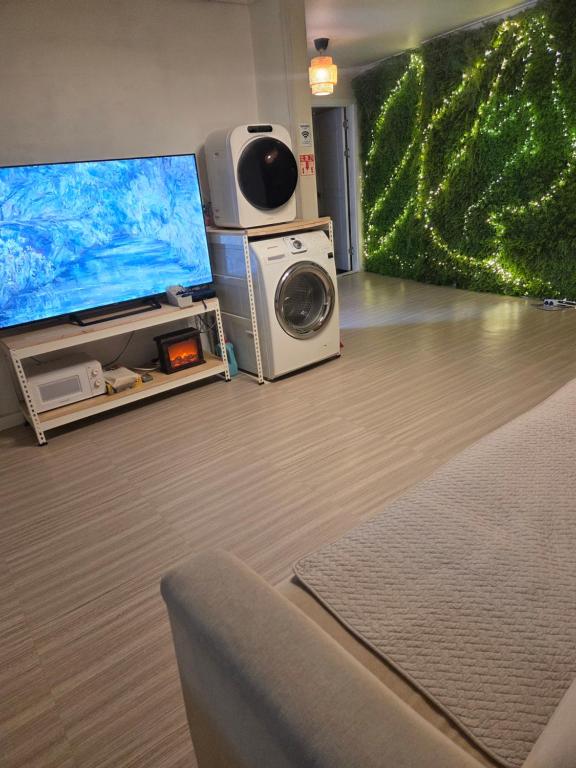 a living room with a tv and a washing machine at Moomoo House in Busan