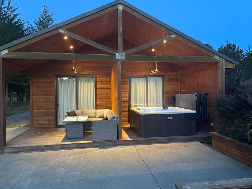 a large wooden cabin with a hot tub on a deck at Whakatā in Te Anau