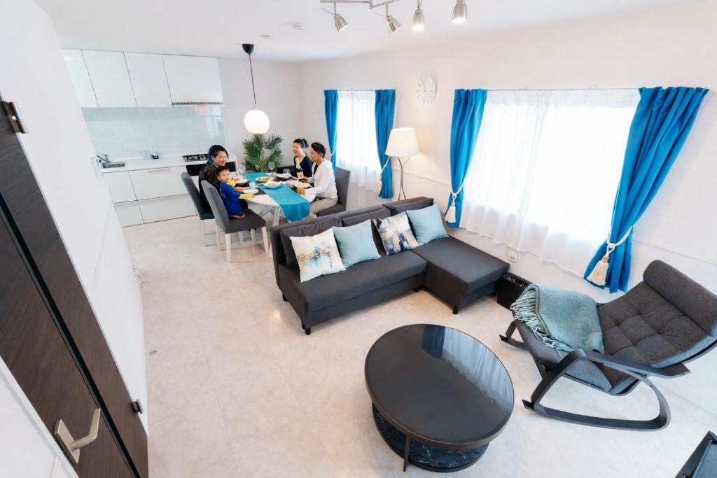 a group of people sitting at a table in a living room at Sunstone Residence 2F - Free Rental Car & Airport Pickup - 10 Min to American Village in Ginowan