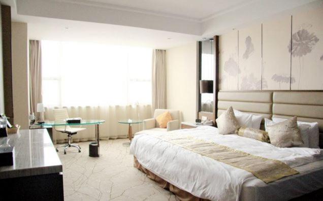una grande camera da letto con un grande letto e una scrivania di Huai'an Jinling Hotel a Huai'an