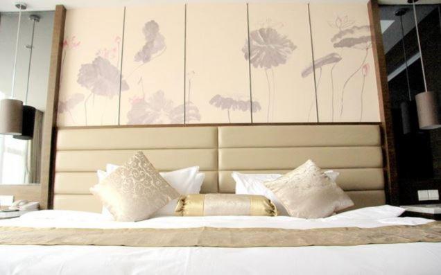 un grande letto con cuscini bianchi e una grande testiera del letto di Huai'an Jinling Hotel a Huai'an