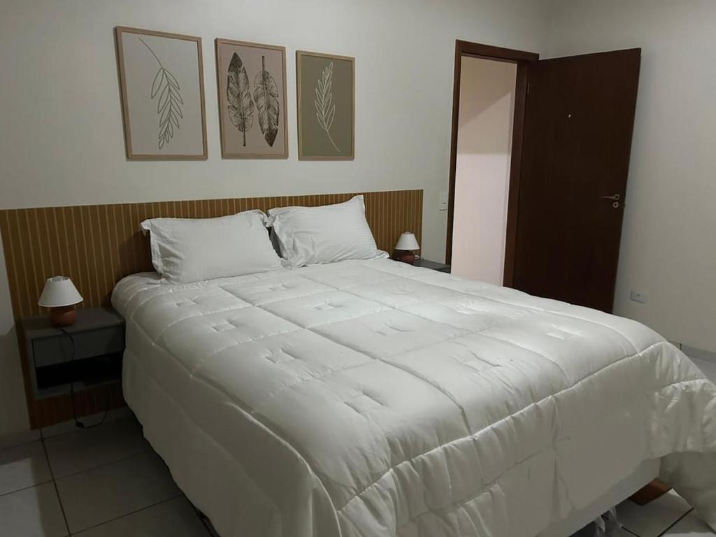 a large white bed in a bedroom with two lamps at Casa aconchego Casa ampla e completa no centro in Naviraí