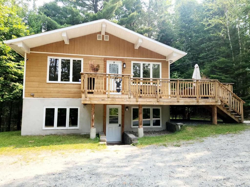 a large wooden house with a large deck at Chalet familial, idéalement situé, billard-table-babyfoot-arcade in Saint-Faustin