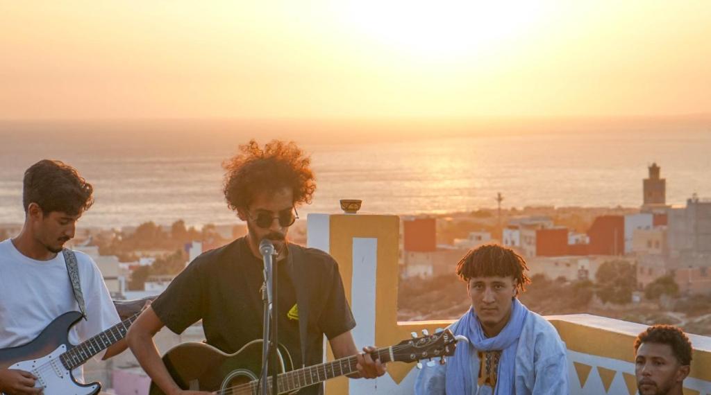 a group of young men playing guitars on a rooftop at Azul Berg Hostel in Tamraght Ouzdar