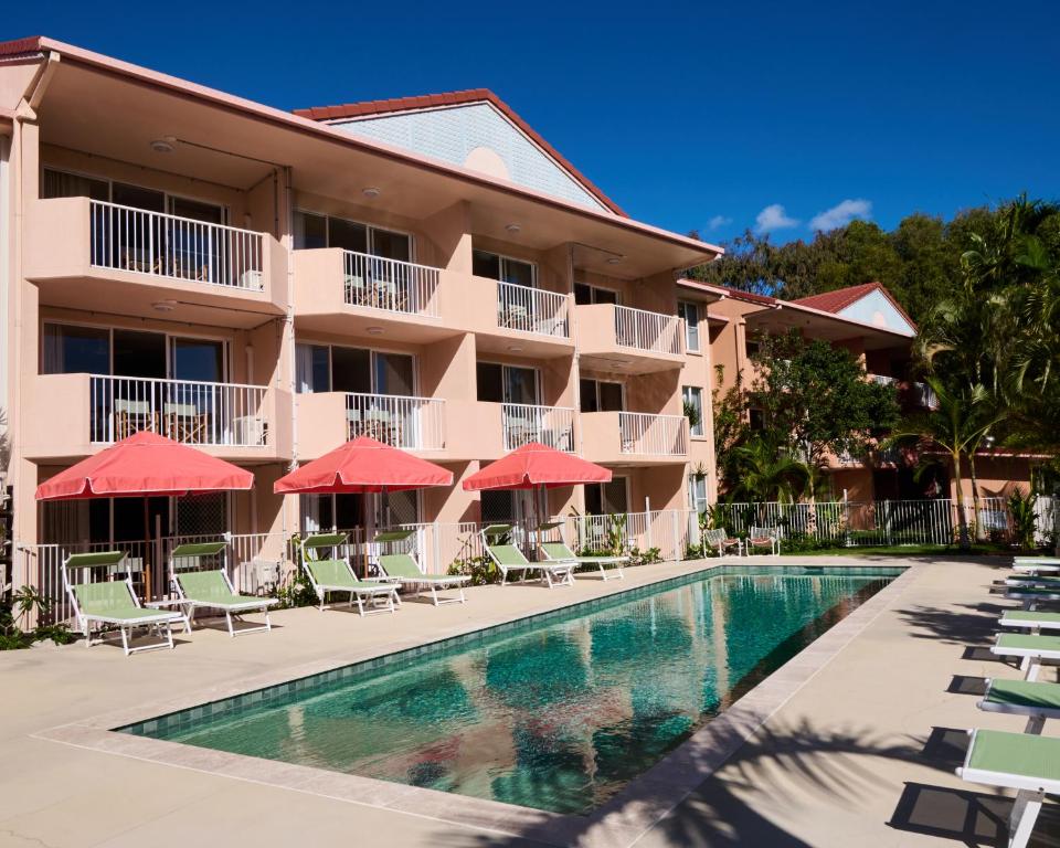 a resort with a swimming pool with chairs and umbrellas at The Roy in Rainbow Beach