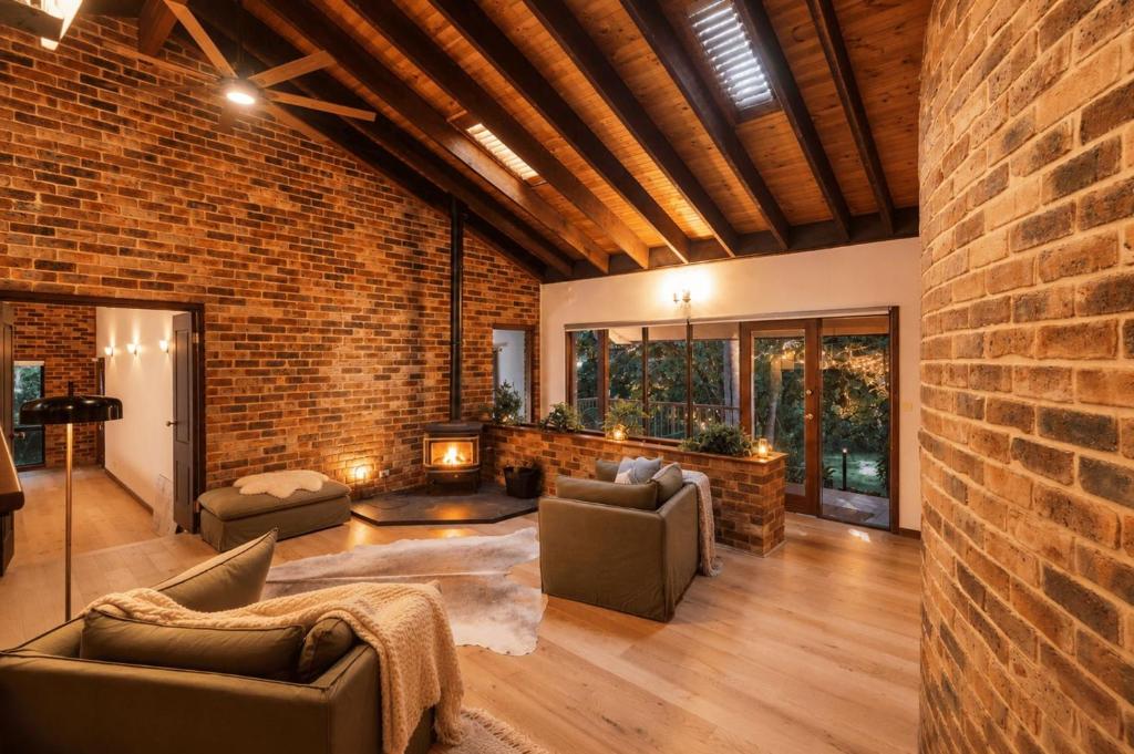 a brick room with two couches and a fireplace at Kookaburra Retreat in Berkeley Vale