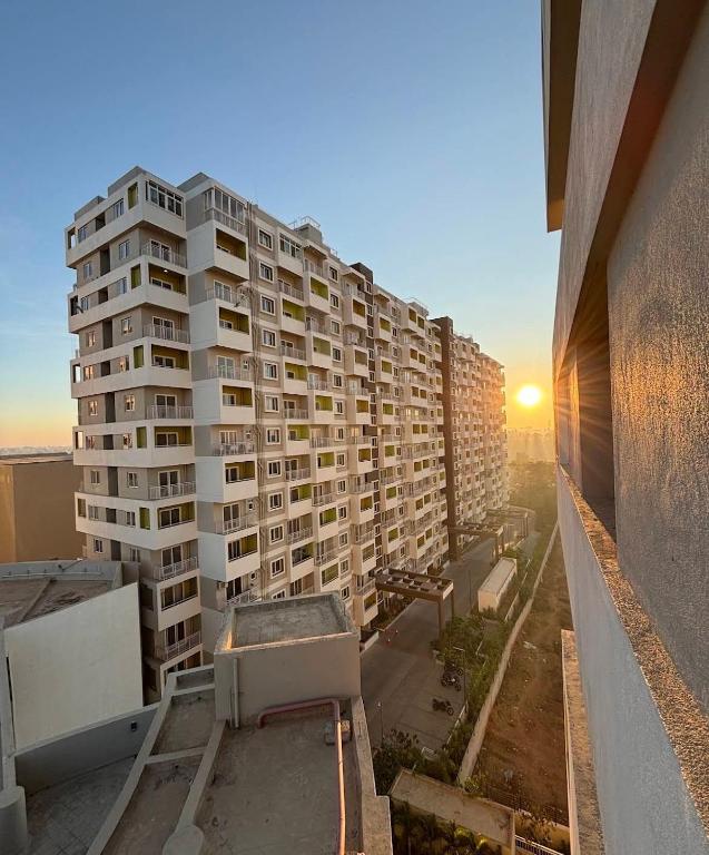 a tall apartment building with the sunset in the background at Beruru Homes- 2BHK Apartment near Bengaluru Airport in Devanhalli