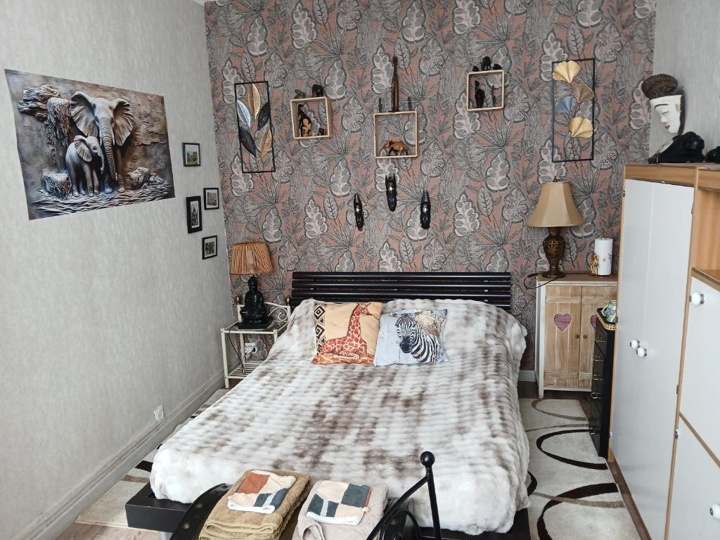 a bedroom with a bed and a wall with pictures at Chambre "Savane Prestige" Esprit Safari Chez Fred in Gorron