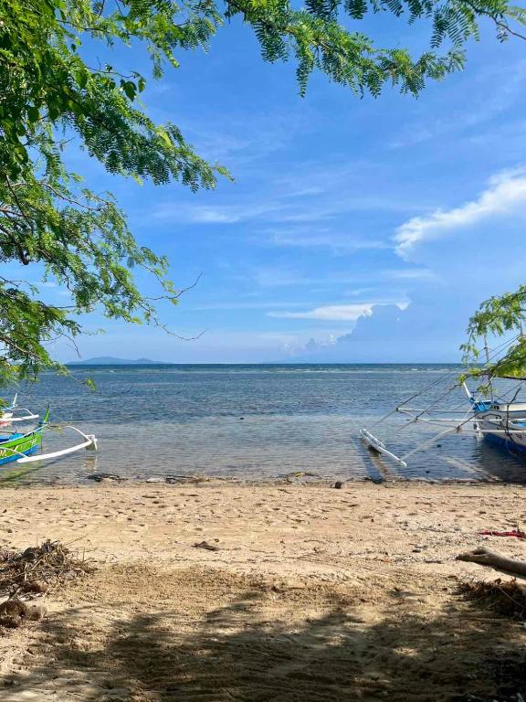 a beach with a boat in the water at Villa Patria in Calatagan