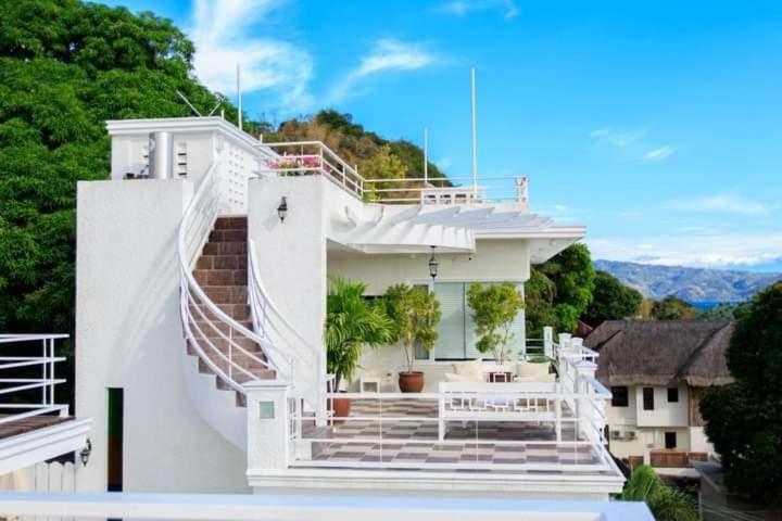 a white house with stairs and a balcony at Casa Bahia Dive Resort in Mabini
