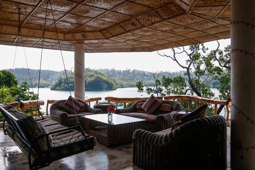 a porch with chairs and a table with a view of a lake at Oceanside Villa in Puerto Galera