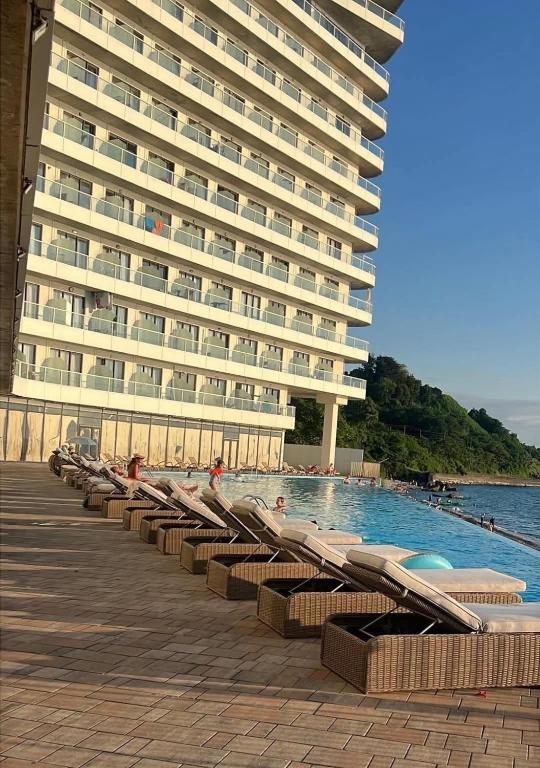 a large building with a swimming pool next to a large building at Bamboo beach tsikhisdziri in Kobuleti