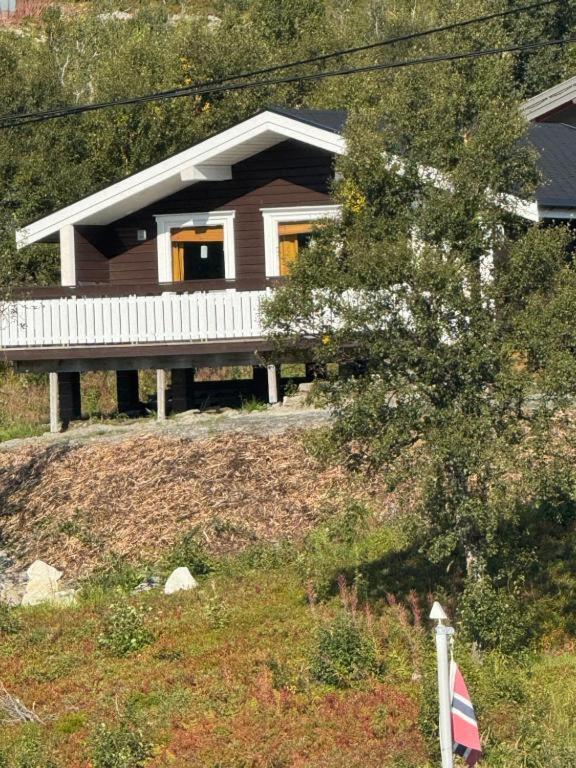 a house on a hill with a flag in front of it at Øse Camping in Gratangen