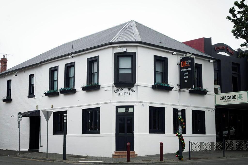 a white building with black windows on a street at Queens Head Hotel in West Hobart