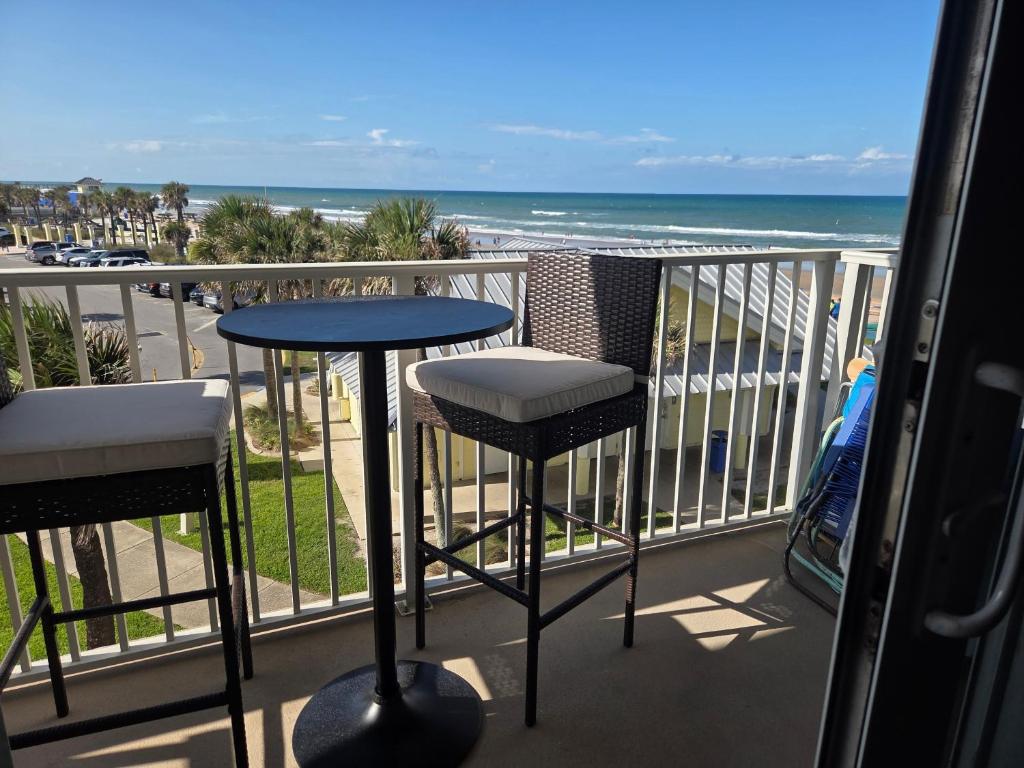 a balcony with a table and chairs and the beach at The Surf Shack at Harbour Beach Resort in Daytona Beach
