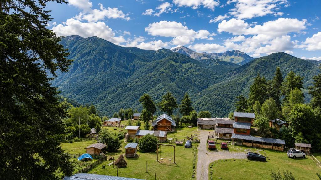 a village in the mountains with mountains in the background at Heshkili huts and cabins Svaneti in Keshkili