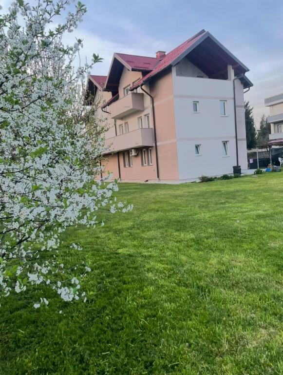a building in a field with a flowering tree at Villa Calypso Sarajevo in Sarajevo