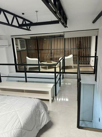 a bedroom with a bed and a balcony with chairs at Moderno loft en el oeste in Cali