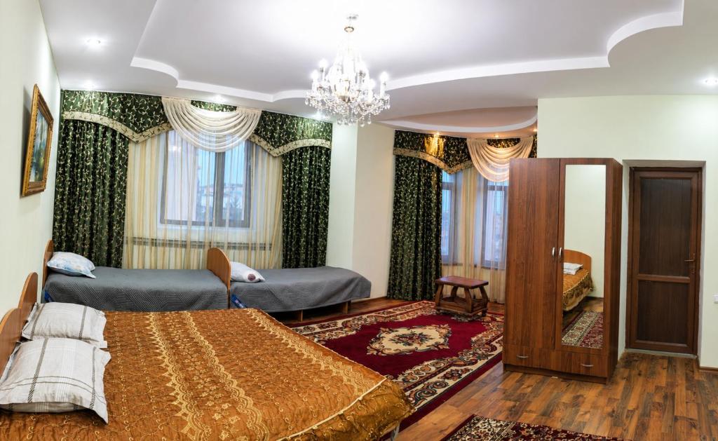 a bedroom with two beds and a chandelier at Гостевой дом RICH in Bosteri