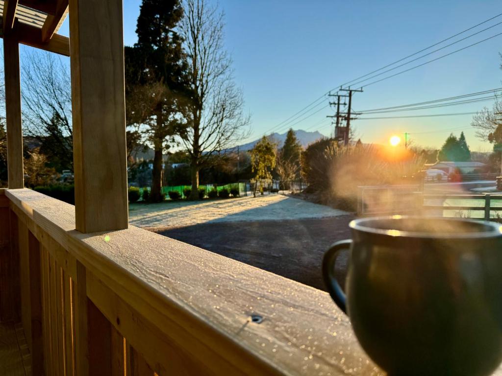 a coffee cup sitting on a porch with a view of a street at Modern Mountain Retreat in Ohakune