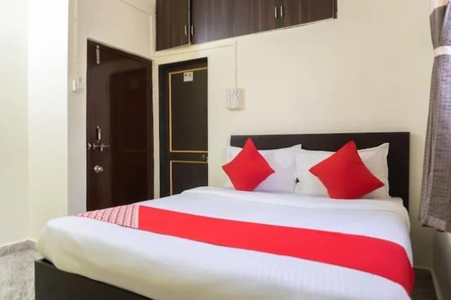 a bedroom with a large bed with red pillows at PL Lodge in Pune