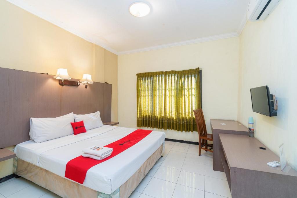 a bedroom with a bed and a desk and a television at RedDoorz near Gubeng Station Surabaya in Bagongpatar