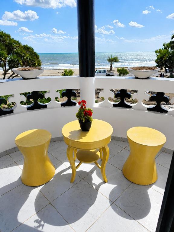 Ein gelber Tisch und zwei Hocker auf einem Balkon mit Blick auf den Strand in der Unterkunft Brise de Mer Sun in Dschibuti