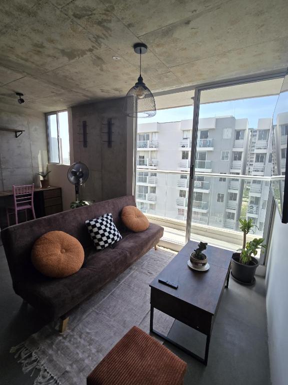a living room with a couch and a large window at Loft type apartment premium style with pool in Barranquilla