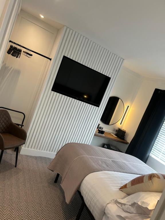 a bedroom with a bed and a flat screen tv on the wall at Bromielaw Room Only Accommodation in Seahouses