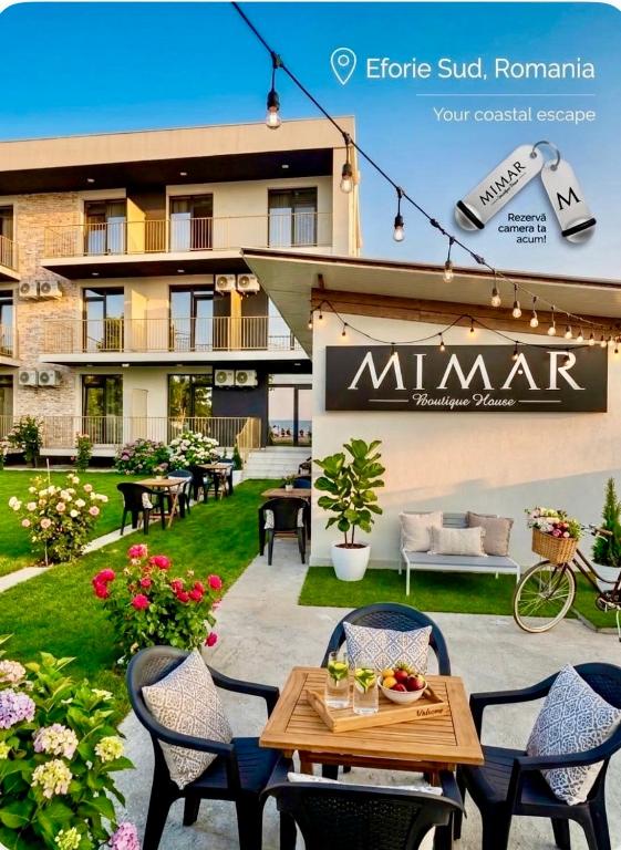 a patio with tables and chairs in front of a building at Mimar Boutique in Eforie Sud