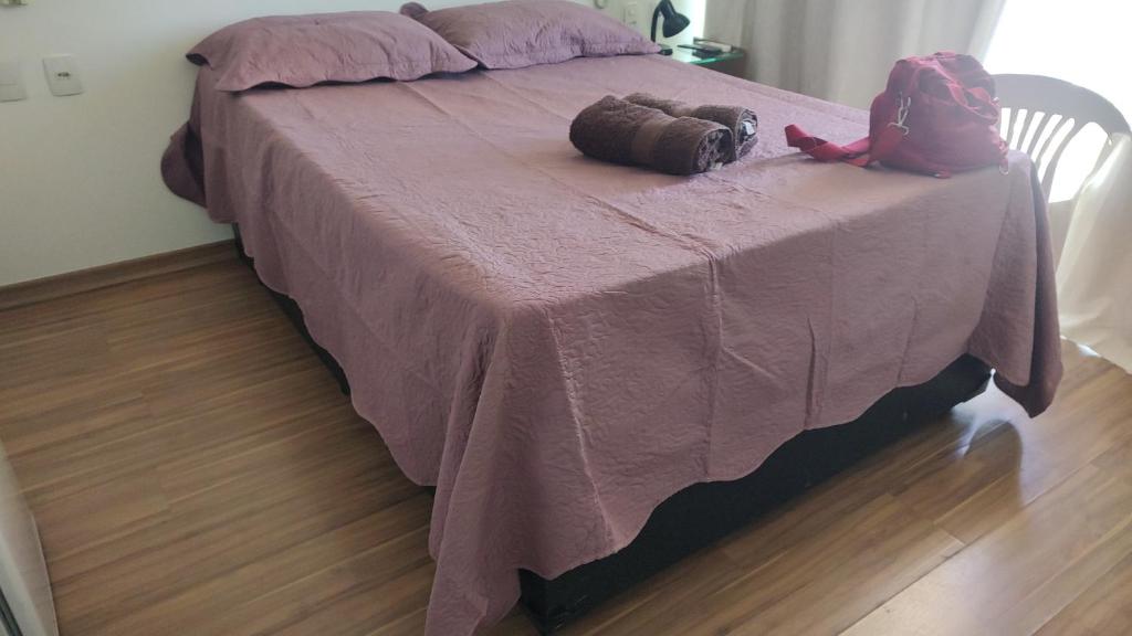 a bed with a purple blanket and a backpack on it at Lagoa Flats com Super Varanda in Lagoa Santa