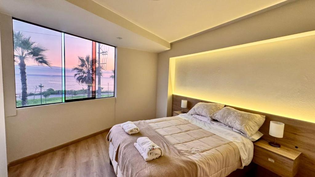 a bedroom with a bed and a large window at Hotel Sunset Mar in Lima