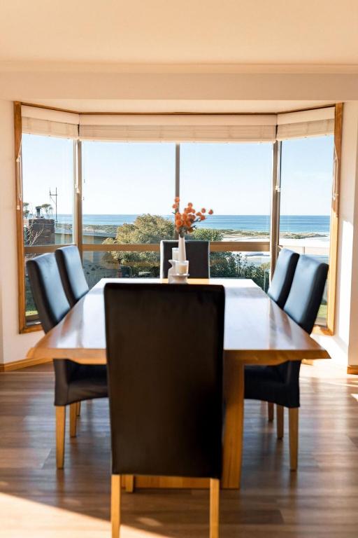 a dining room with a table and a view of the ocean at Drift - Watch the world go by in Scamander