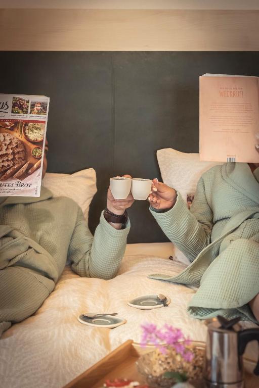 two people sitting on a bed drinking coffee at das Ebner in Stubenberg