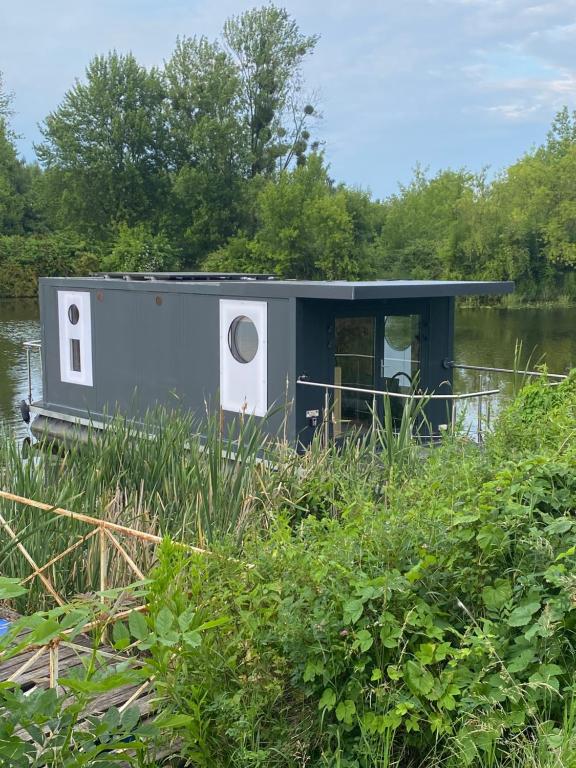 a tiny house sitting on the side of a river at Pływający Dom in Zegrze